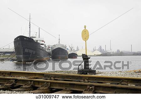 Stock Photo - Train track, switch stand, and ships against industrial back drop, Hamilton, Ontario.. Fotosearch