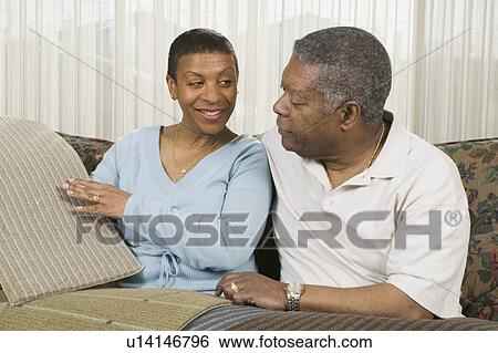Stock Photograph - African American couple going over carpet samples, Vancouver, BC. Fotosearch