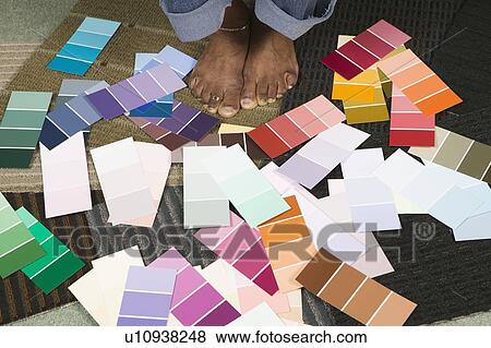 Stock Photo - African American going over paint colour swatches, Vancouver, BC. Fotosearch