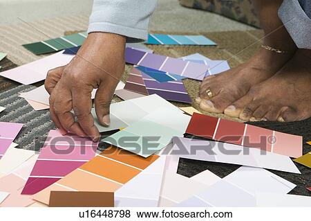 Stock Photo - African American going over paint colour swatches, Vancouver, BC. Fotosearch