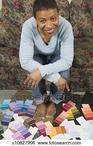 Stock Photograph - African American going over paint colour swatches, Vancouver, BC. Fotosearch