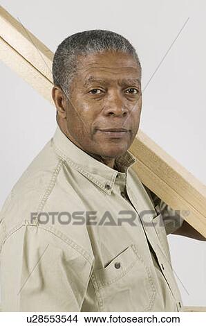Picture - African American Man Doing Home Improvement, Carrying 2x4 Lumber Over Shoulder, Vancouver, BC. Fotosearch