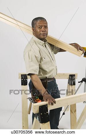 Stock Photograph - African American Man Doing Home Improvement, Carrying 2x4 Lumber Over Shoulder, Vancouver, BC. Fotosearch