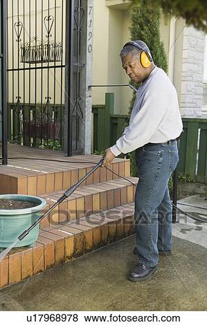 Stock Photo - African American man using a power washer, Vancouver, BC. Fotosearch