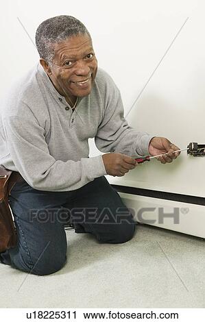 Stock Image - African American man working on a household receptacle, Vancouver, BC. Fotosearch