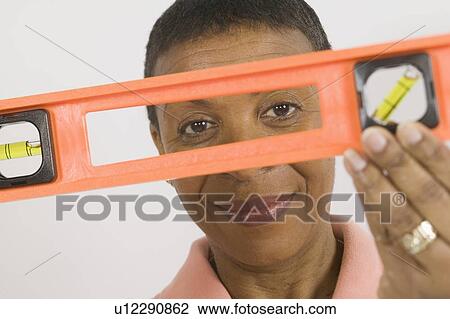 Stock Image - African American Woman Doing Home Improvement, Using a Spirit Level, B. C.. Fotosearch