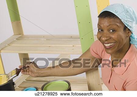 Stock Photography - African American Woman Doing Home Improvement Painting, Canada, British Columbia. Fotosearch