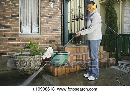 Stock Photo - African American woman using a power washer, Vancouver, BC. Fotosearch
