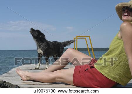 Stock Image - Woman and dog on dock; Canada, Manitoba, Riding Mountain National Park. Fotosearch