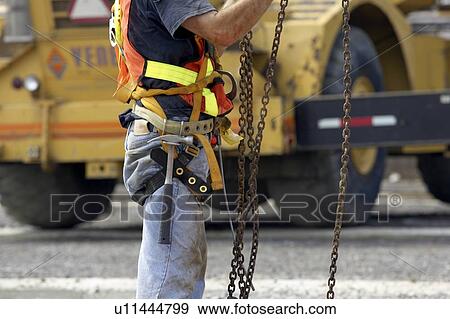 Construction worker in harness and tool belt adjusting chains; Canada, Ontario, Hamilton (Composting Facility) View Large Photo Image Stock Photo - Construction worker in harness and tool belt adjusting chains; Canada, Ontario, Hamilton (Composting Facility). Fotosearch