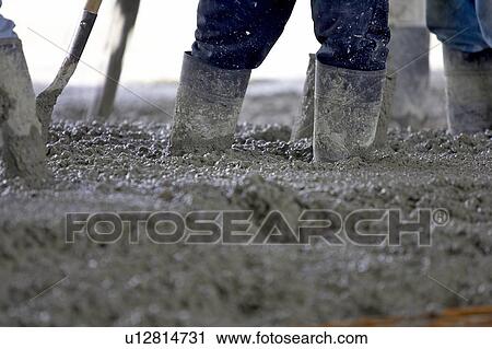 Stock Image - Detail of workers wearing rubber boots in cement; Canada, Ontario, Hamilton(Composting Facility). Fotosearch