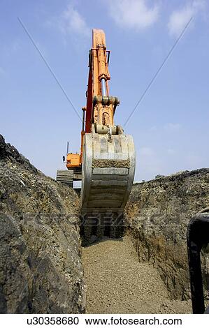 Stock Image - Excavator filling in section of drainage pipe with dirt; Canada, Ontario, Hamilton (Composting Facility). Fotosearch