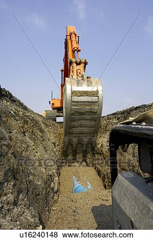 Stock Photo - Excavator filling in section of drainage pipe with dirt; Canada, Ontario, Hamilton (Composting Facility). Fotosearch