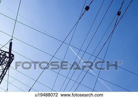 Stock Image - Jet contrail in midst of electric lines; Canada, Ontario. Fotosearch