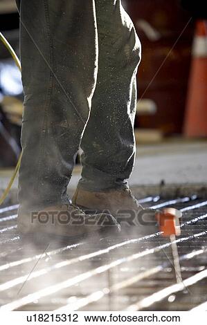 Stock Image - Worker walking on concrete form made of rebar; Canada, Ontario, Hamilton. Fotosearch