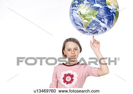 Stock Image - 9 year old girl balances the globe on her finger. Fotosearch
