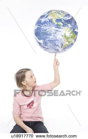 Stock Image - 9 year old girl balances the globe on her finger. Fotosearch