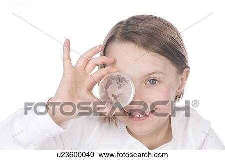 Stock Image - 9 year old girl with the glass globe in front of her face. Fotosearch