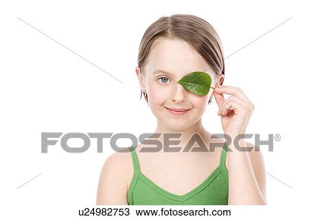 Stock Image - 9 year old girl with the green leaf in front of her face. Fotosearch