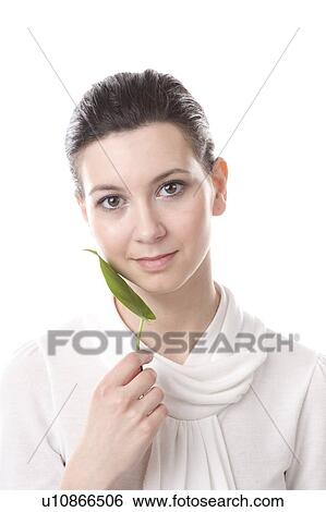 Stock Photograph - face of a young woman with a leaf touching her cheek. Fotosearch