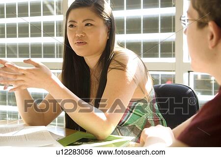 Stock Photograph - Female student seated, talking, in front of solar panelled windows, Winnipeg, Canada. Fotosearch