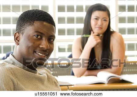 Stock Image - Male student foreground, female student background, in front of solar panelled windows, Winnipeg, Canada. Fotosearch