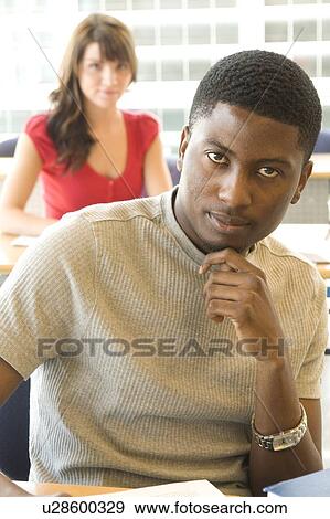 Stock Photo - Male student foreground, female student background, in front of solar panelled windows, Winnipeg, Canada. Fotosearch