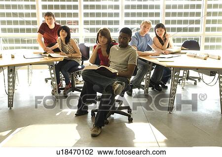 Stock Image - Portrait of students seated at tables in front of solar panelled windows, Winnipeg, Canada.. Fotosearch