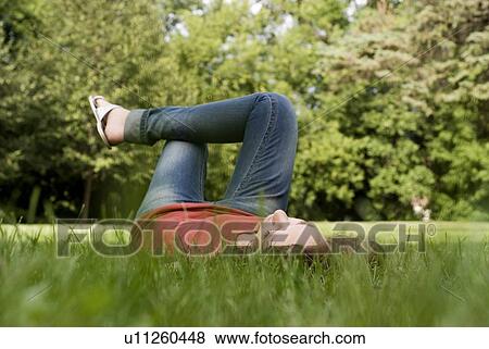 Stock Photo - Relaxed woman lying in the grass, Munson Park, Winnipeg, Canada. Fotosearch