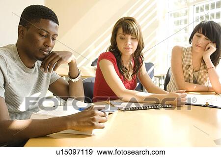 Stock Photo - Three students seated at table, Winnipeg, Canada. Fotosearch