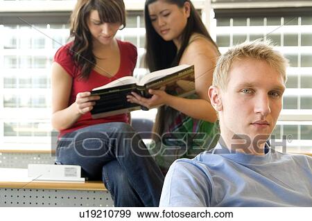 Stock Photo - Two female students in background, male in foreground, in front of solar panelled windows, Winnipeg, Canada. Fotosearch