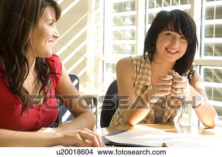 Picture - Two students seated, talking, in front of solar panelled windows, Winnipeg, Canada.. Fotosearch