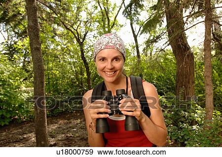 Stock Photo - Woman in woods with binoculars, Regina, Saskatchewan. Fotosearch