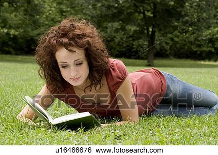 Stock Photograph - Woman on the grass reads a book, Munson Park, Winnipeg, Canada. Fotosearch