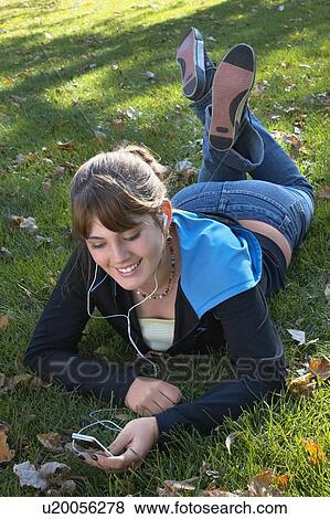 Young woman listening to Ipod outdoors, Brantford, Ontario View Large Photo Image Stock Photo - Young woman listening to Ipod outdoors, Brantford, Ontario. Fotosearch