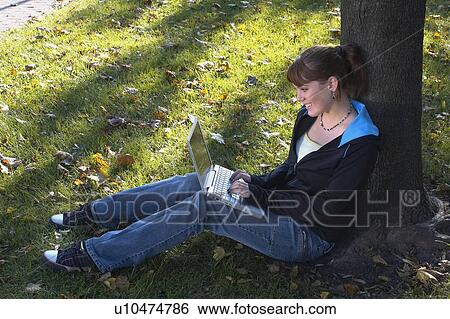 Young woman using laptop outdoors, Brantford, Ontario View Large Photo Image Stock Photograph - Young woman using laptop outdoors, Brantford, Ontario. Fotosearch
