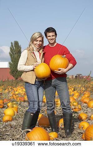 Stock Image - Couple in organic pumpkin patch, Ladner, British Columbia, Canada. Fotosearch