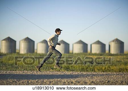 Farmer running on gravelled road in front of row of steel grain bins, Saskatchewan, Canada View Large Photo Image Stock Image - Farmer running on gravelled road in front of row of steel grain bins, Saskatchewan, Canada. Fotosearch