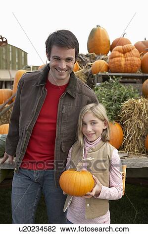 Stock Image - Father with daughter holding organic pumpkin, Ladner, British Columbia, Canada. Fotosearch