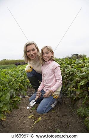 Mother and daughter kneeling together in organic garden, Ladner, British Columbia, Canada View Large Photo Image Stock Photo - Mother and daughter kneeling together in organic garden, Ladner, British Columbia, Canada. Fotosearch