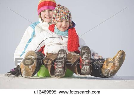 Stock Photography - 13 and 9 year olds slide down hill, Winnipeg, Canada. Fotosearch