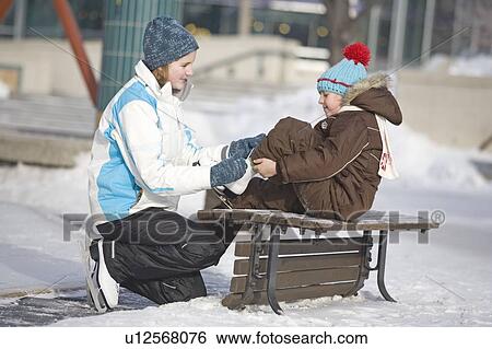 13 year-old girl helps 9 year-old girl tie skates, at The Forks, Winnipeg, Canada View Large Photo Image Stock Photograph - 13 year-old girl helps 9 year-old girl tie skates, at The Forks, Winnipeg, Canada. Fotosearch