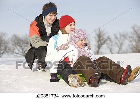 Picture - 15, 13 and 9 year olds prepare to slide down hill, Winnipeg, Canada. Fotosearch