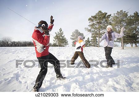 Stock Image - 3 kids (14, 13, and 9) throw snow at each other, Winnipeg, Canada. Fotosearch