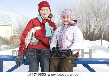 Stock Image - 9 and 13 year old girls resting on bench, skating trails, The Forks, Winnipeg, Canada. Fotosearch