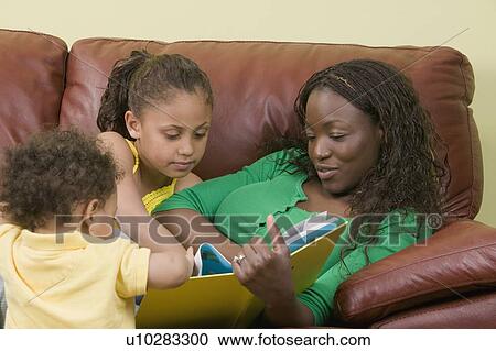 Stock Image - African American mom and Mulatto girl 6 years. Reading.. Fotosearch