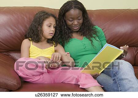 Stock Photo - African American mom and Mulatto girl 6 years. Reading.. Fotosearch