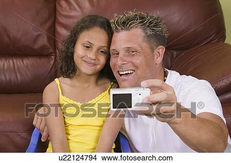 Picture - Caaucasian father taking picture of self and Mulatto daughter (6 years old). Fotosearch