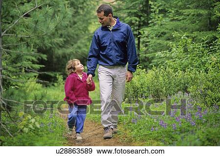 Stock Photo - Dad walks with daughter on forest trail, looking at each other, Whistler, BC. Fotosearch