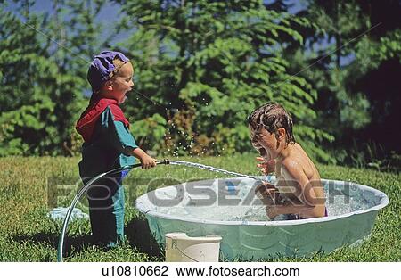 Girl, 3, sprays boy, 5, in plastic pool, Whistler, BC View Large Photo Image Stock Image - Girl, 3, sprays boy, 5, in plastic pool, Whistler, BC. Fotosearch